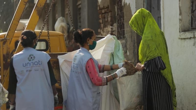Unnati employees collecting waste from a resident